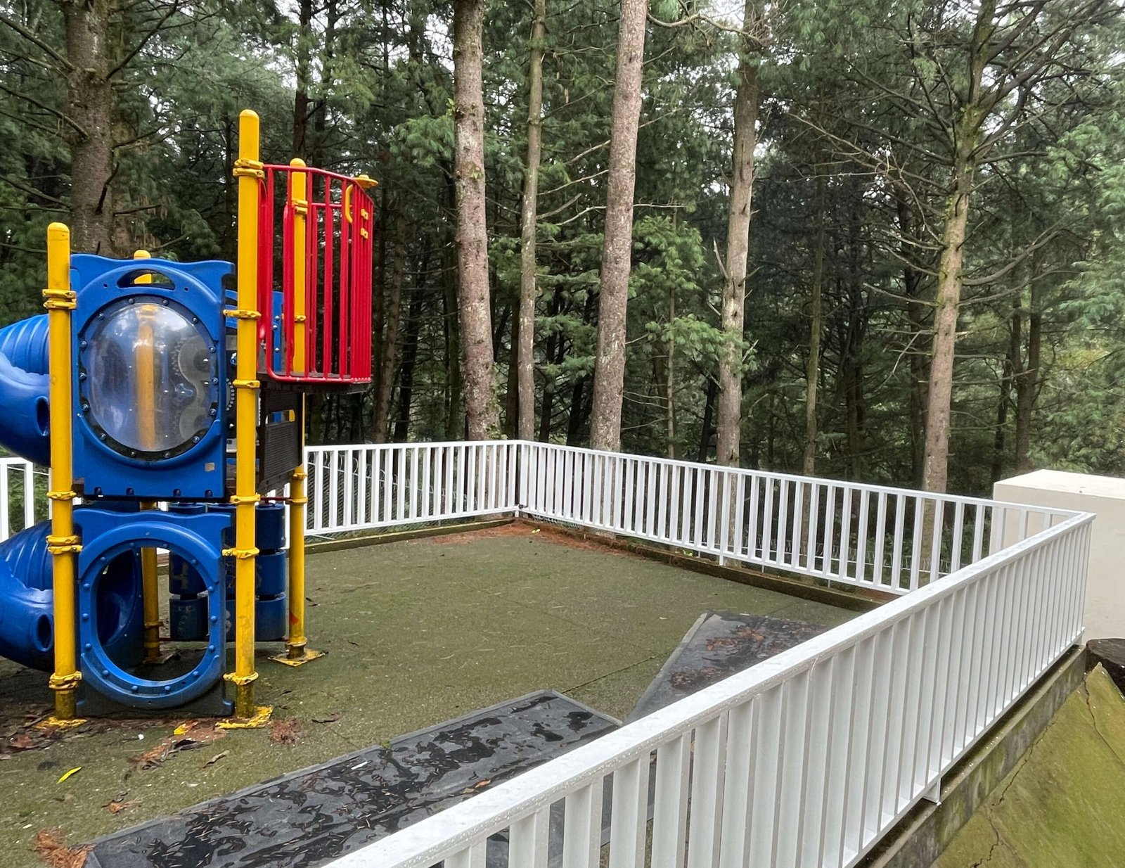 Se muestran unos juegos infantiles plasticos en una escuela en un escenario boscoso